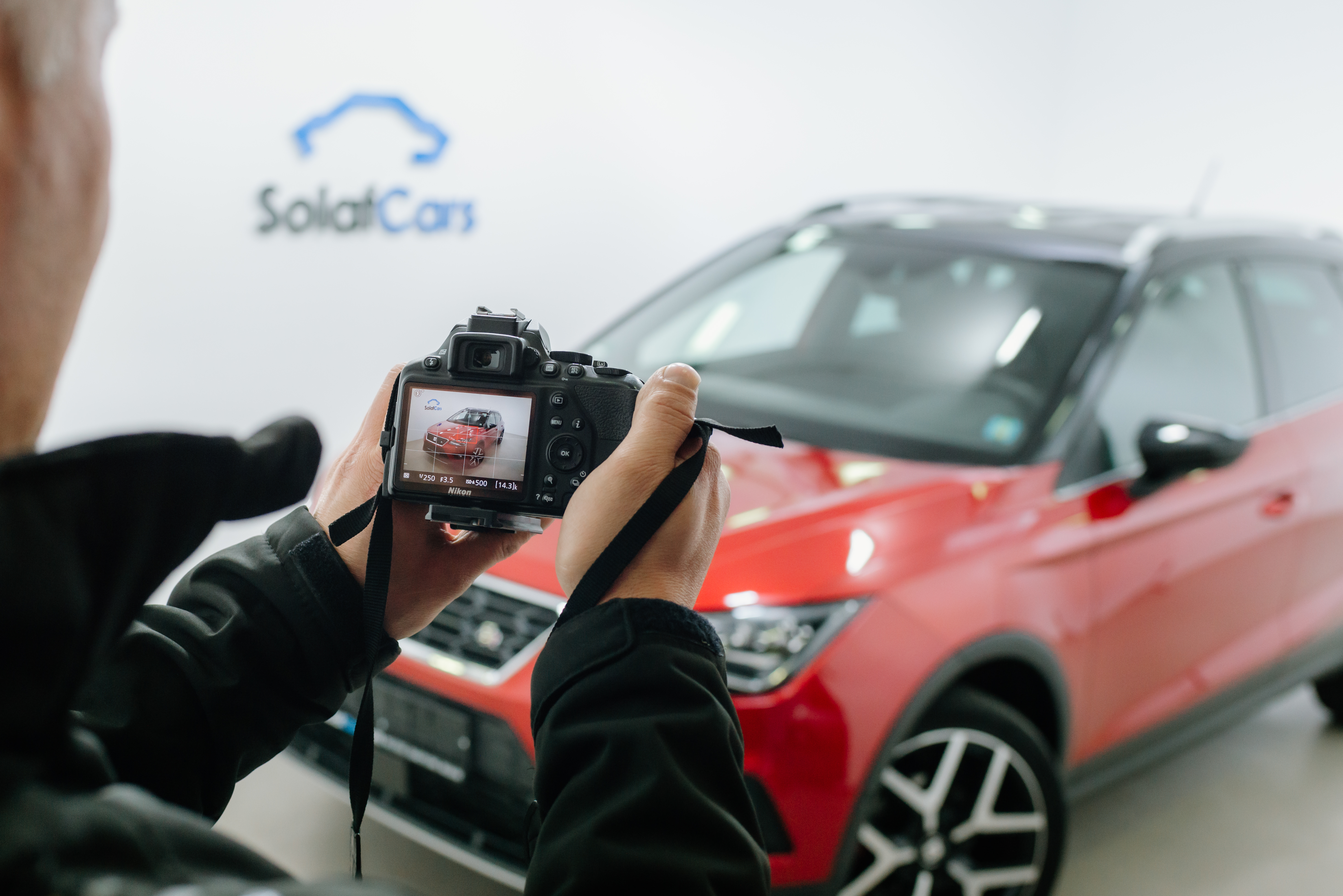 Човек изблиза који фотографише дслр камером црвени аутомобил у фото студију
